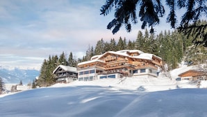 A large, multi-story chalet with a ski lift, surrounded by snow-covered trees and mountains. - Frieden (Pill)