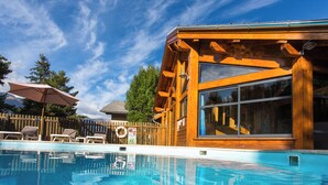 Eine Holzhütte mit Pool, einer Holzterrasse und einem großen Fenster.