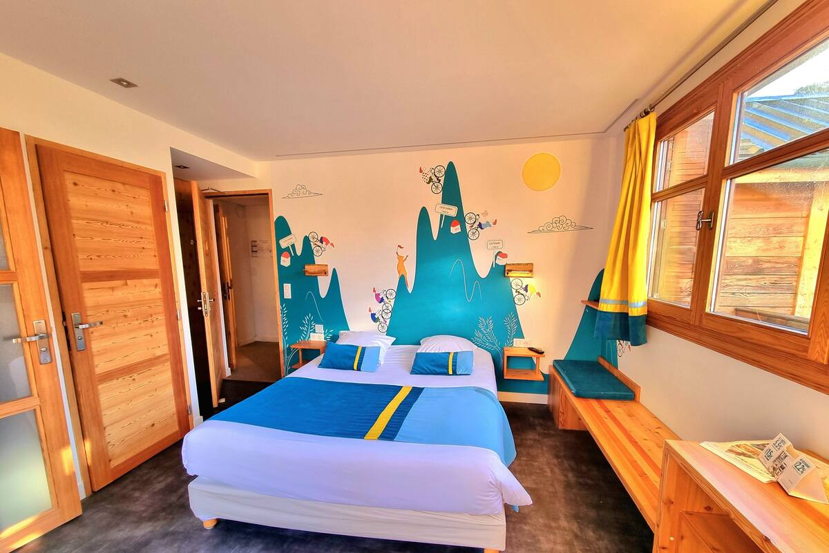 Une chambre à coucher avec un lit, un bureau, une chaise et une fenêtre avec des rideaux.
