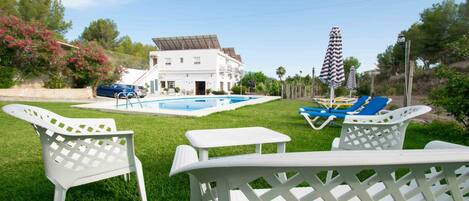 A pool area with lounge chairs and a white building in the background.