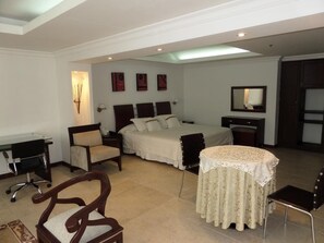 Een hotelkamer met een bed, een bureau, een stoel, een klein tafeltje en een spiegel.