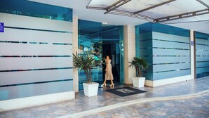 A modern building entrance with glass doors, potted plants, and a tiled floor.