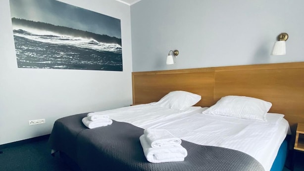 A hotel room with a large bed, two pillows, a headboard, a wall-mounted lamp, and a framed picture of a seascape. - Centrum Galion (Gda?sk)