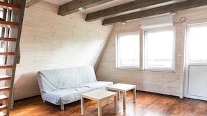 A room with a wooden floor, a sofa, two small tables, a window, and a ladder. - Centrum Galion (Gda?sk)