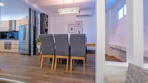 A modern kitchen with built-in appliances, a dining area with a table and chairs, and a pendant light fixture. - Hotel NG (Cartagena)