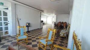 A spacious hallway with checkered flooring, golden chairs, and a white door with glass panels. - Hotel NG (Cartagena)
