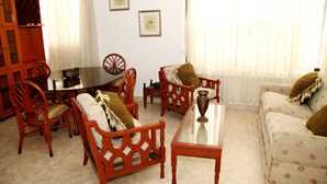 A living room with a round table, wooden chairs, a sofa, and a coffee table. - Hotel NG (Cartagena)