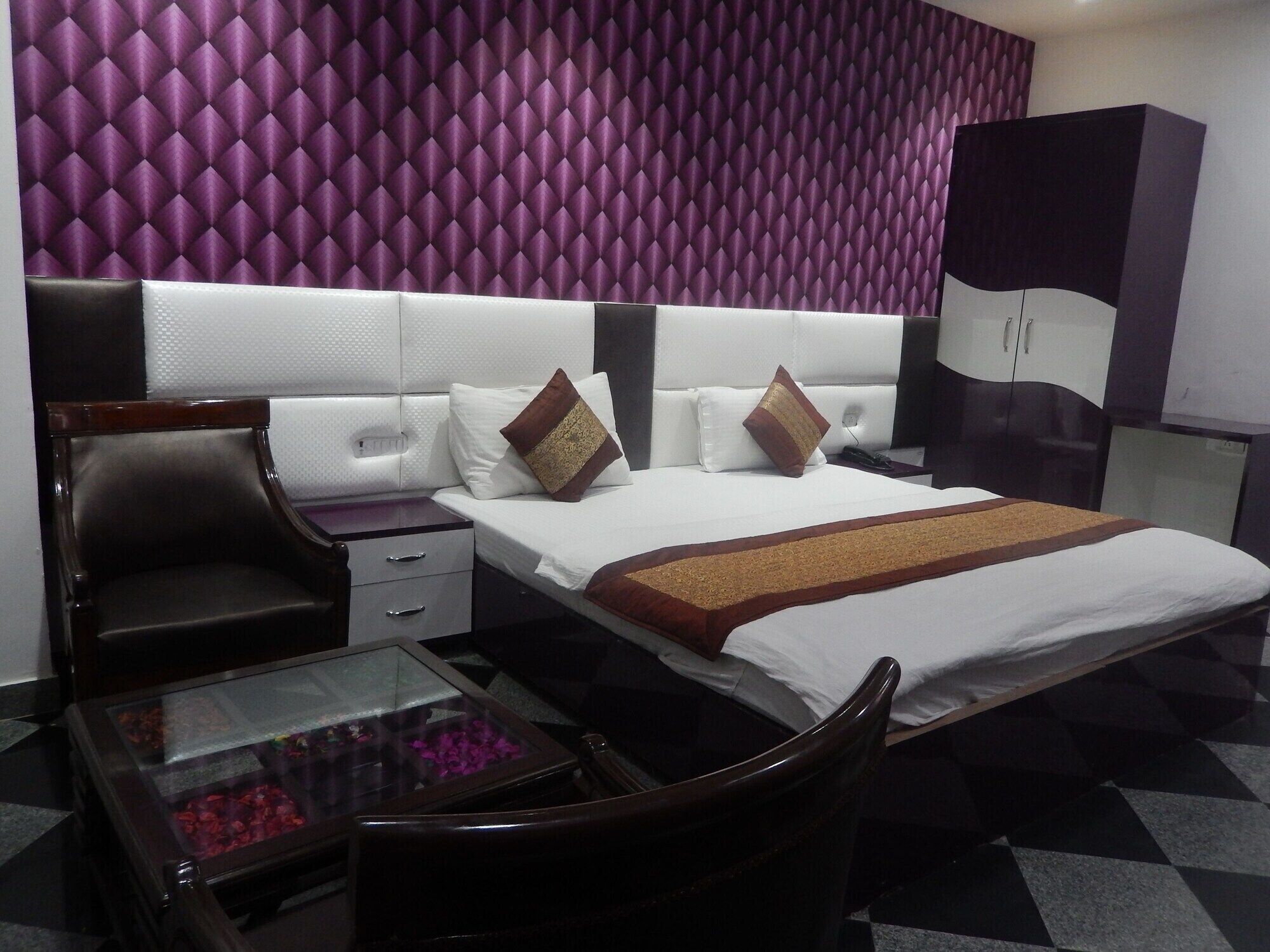 A hotel room with a bed, a desk, a chair, a wardrobe, and a decorative wall.