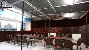 A restaurant with multiple tables and chairs, a tiled floor, and a ceiling with a fan. - Orchid Garden (New Delhi)