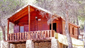 Una cabaña de madera con balcón, base de piedra y un letrero con el número "606".