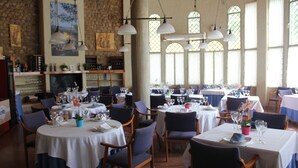 Un restaurante con mesas redondas, sillas y lámparas colgantes.