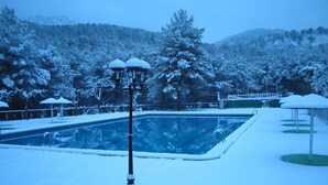 Una piscina al aire libre cubierta de nieve con vista despejada del paisaje nevado circundante y montañas.