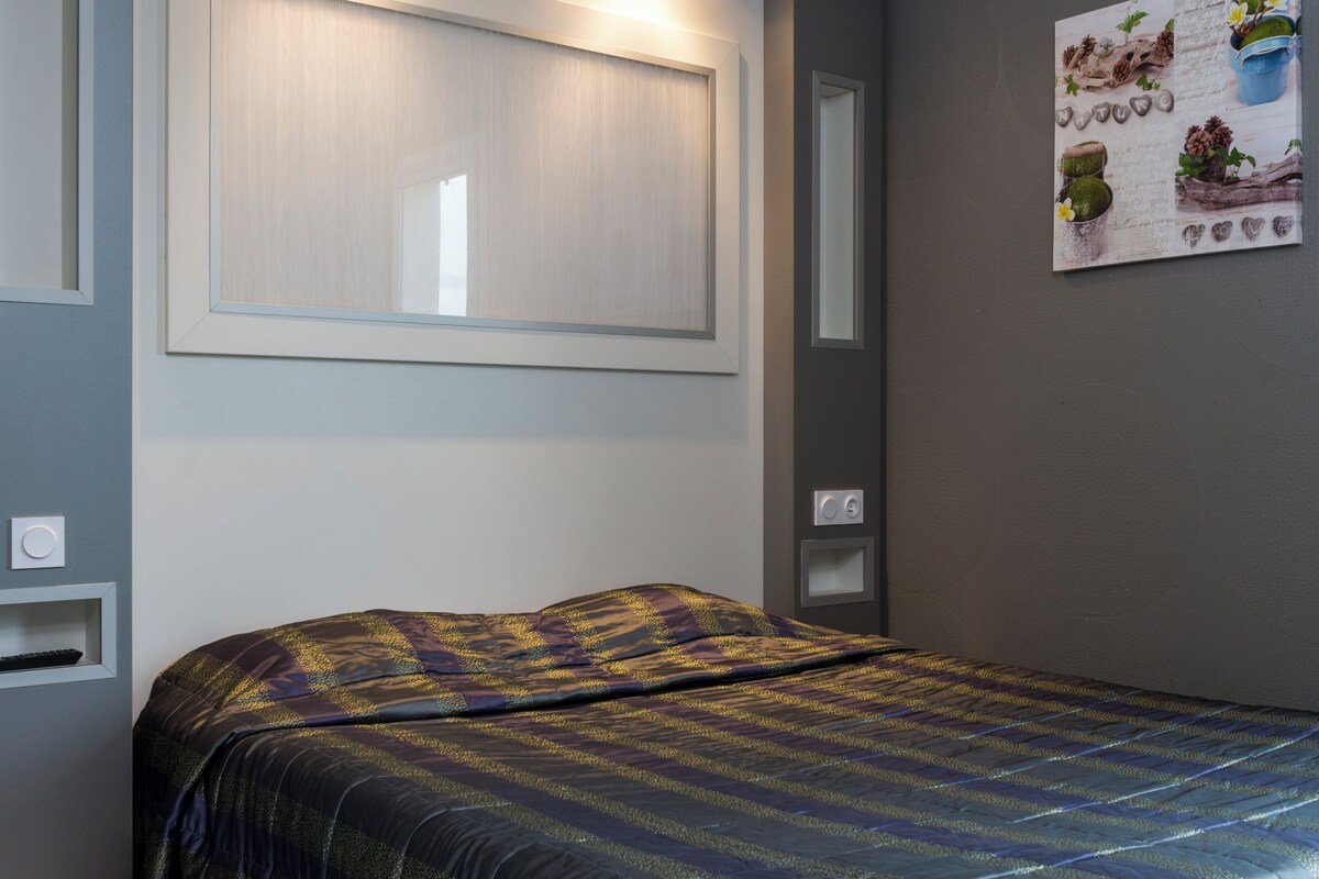 Une chambre à coucher avec un lit, une lampe fixée au mur et une petite étagère.