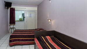Une pièce avec deux lits, une chaise, une porte et une fenêtre.