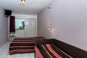 Una habitación con dos camas, una silla, un televisor y una puerta con ventanal.