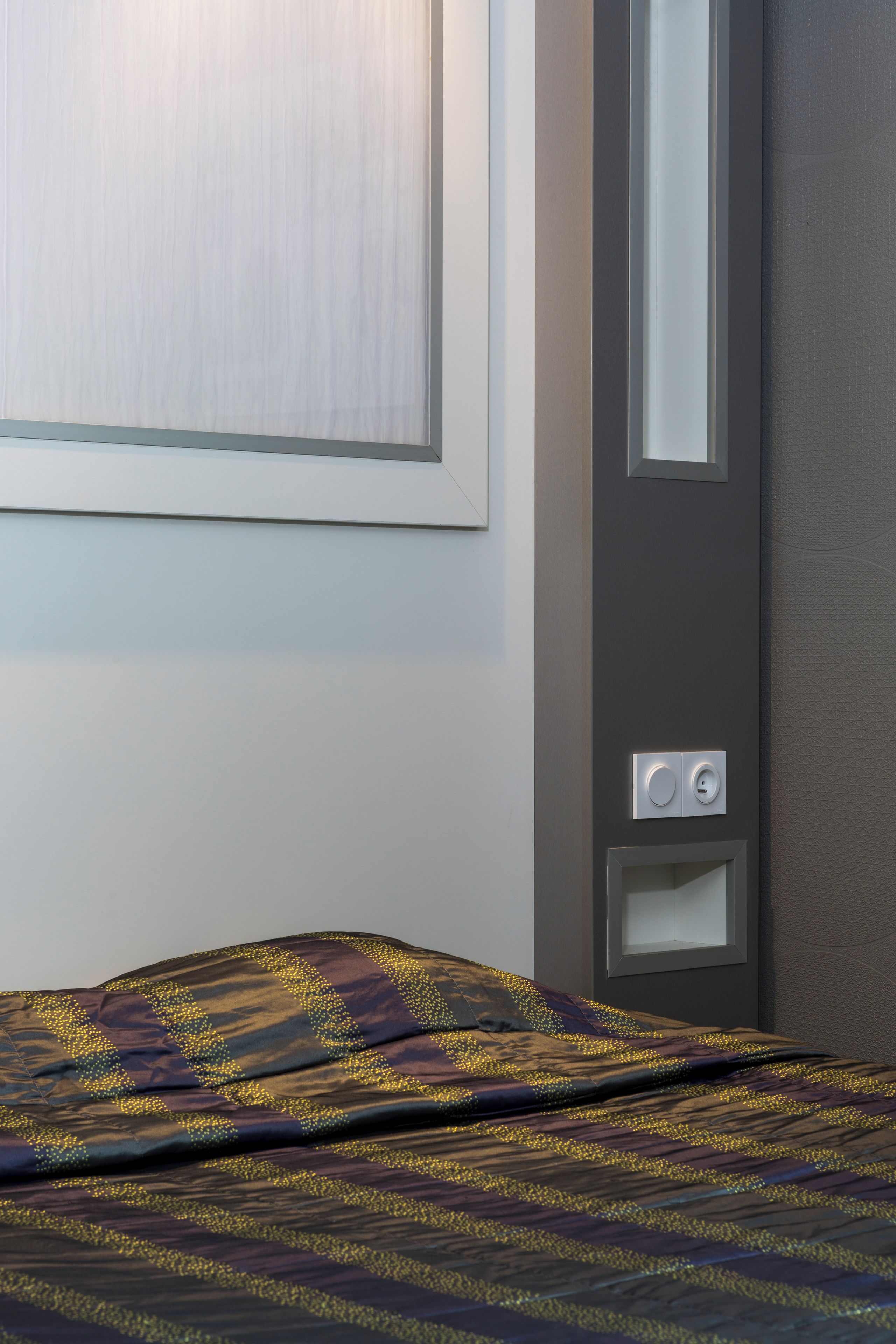 Una habitación de hotel con una cama, un interruptor de luz en la pared y una puerta.