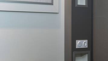 Una habitación de hotel con una cama, un interruptor de luz en la pared y una puerta.