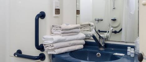 Un baño con inodoro blanco, lavamanos azul y espejo.