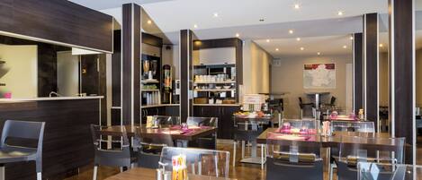 A modern restaurant interior with high tables, chairs, and a bar area.