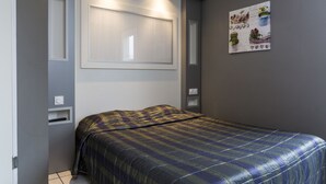 Un dormitorio con cama, ventana, una obra de arte en la pared e iluminación empotrada.