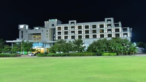 A modern hotel with multiple floors, a well-maintained lawn in front, and a visible restaurant sign. - The Grand Bhagwati Seasons Rajkot (Rajkot)