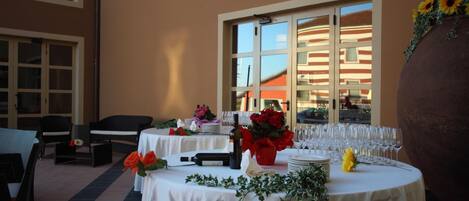 Un comedor interior con mesas redondas, sillas y un jarrón grande con flores.