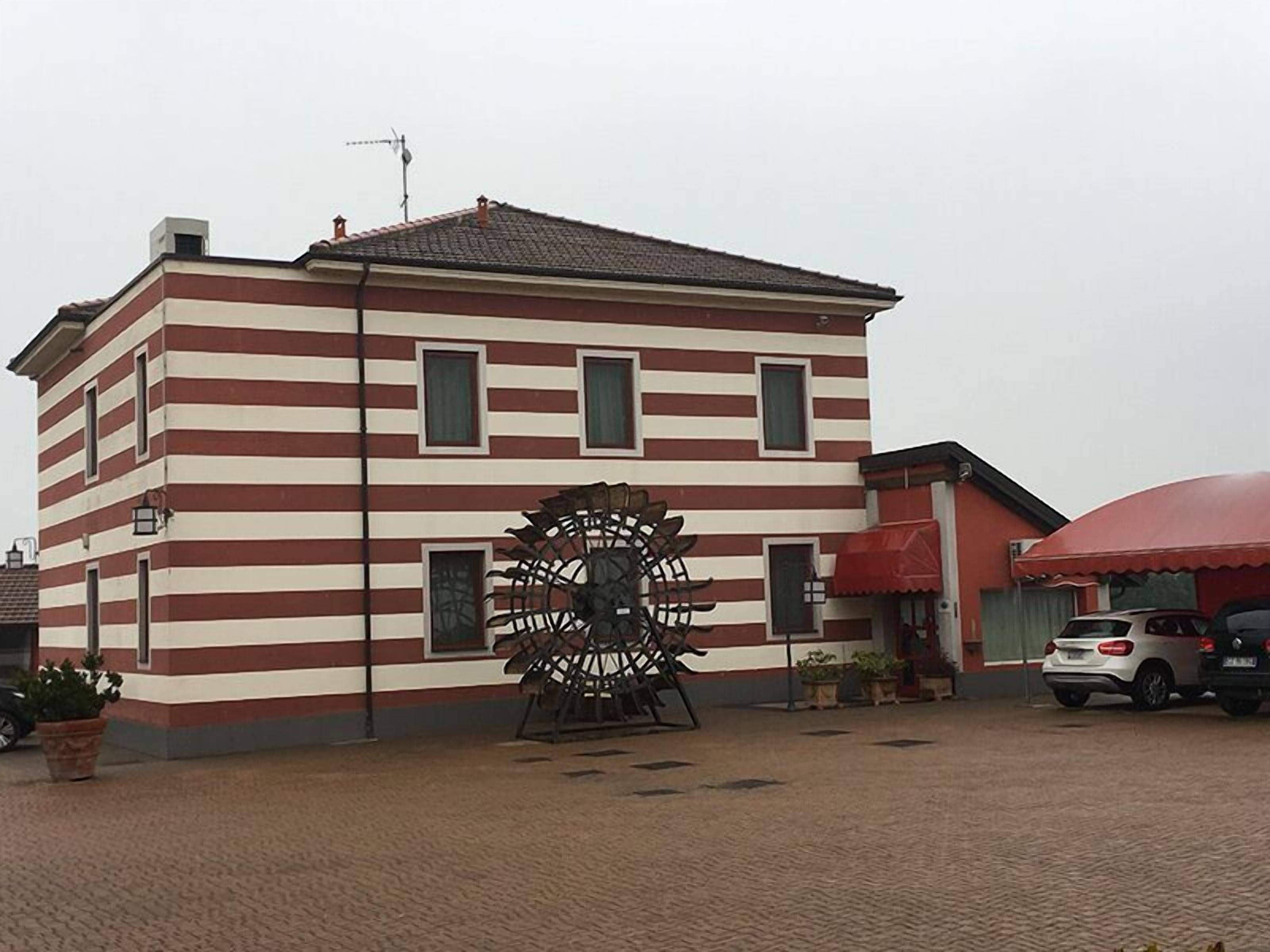 Un edificio con fachada a rayas y un molino de viento grande al frente.