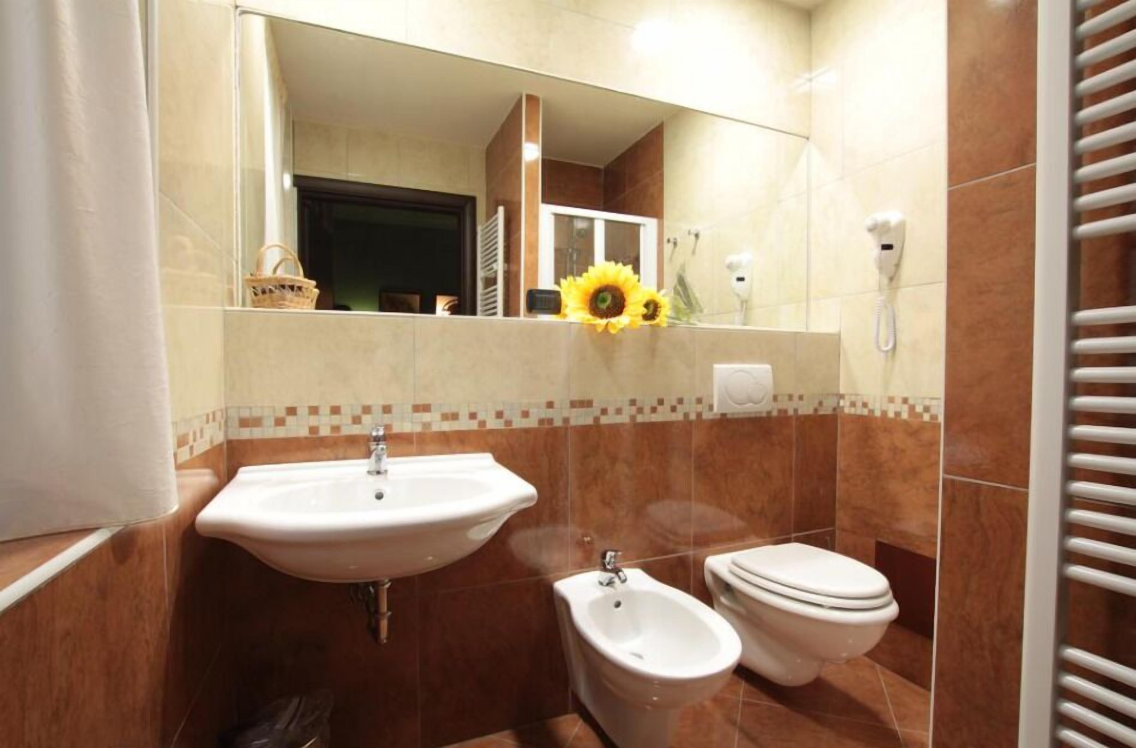 Un bagno con lavandino, bidet, wc e specchio.