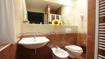Un bagno con lavandino, bidet, wc e specchio.