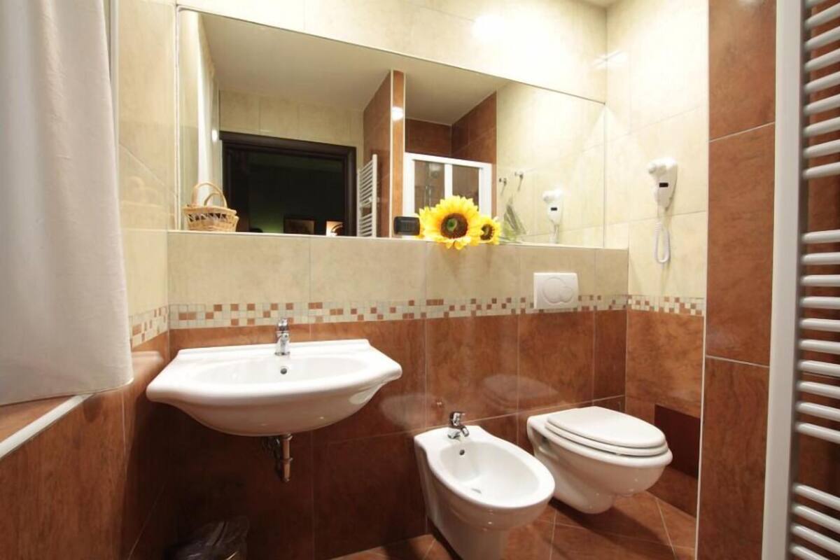 A bathroom with a sink, bidet, toilet, and a mirror.
