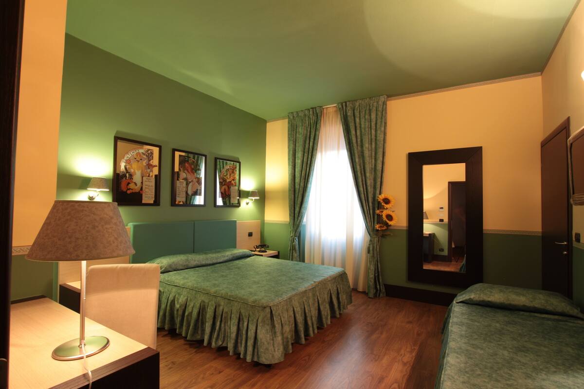 A bedroom with a bed, a chair, a lamp, and a mirror.