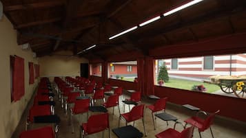 Un comedor con sillas y mesas rojas, vigas de madera en el techo y vistas a un edificio de fachada a rayas rojas y blancas.