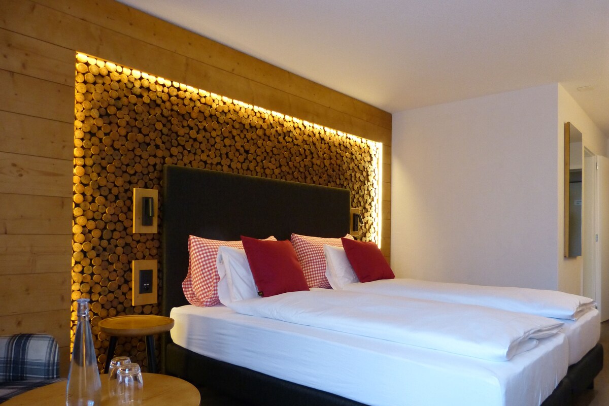 Una habitación de hotel con una cama grande, una mesa redonda de madera y una pared decorada con troncos.