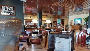 A modern lounge area with leather sofas, a bar, and a wooden ceiling. - Steinmattli Hotel (Adelboden)