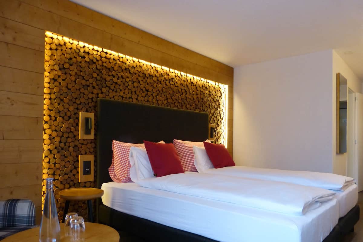 A hotel room with a large bed, a round wooden table, and a wall decorated with wooden logs.