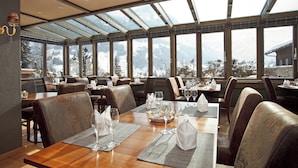 A restaurant with tables set for dining, large windows, and a view of mountains.