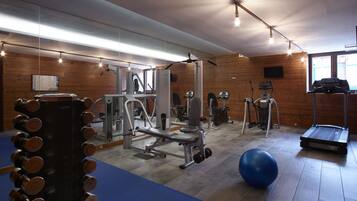 A gym with various exercise equipment, including dumbbells, a bench press, and cardio machines.