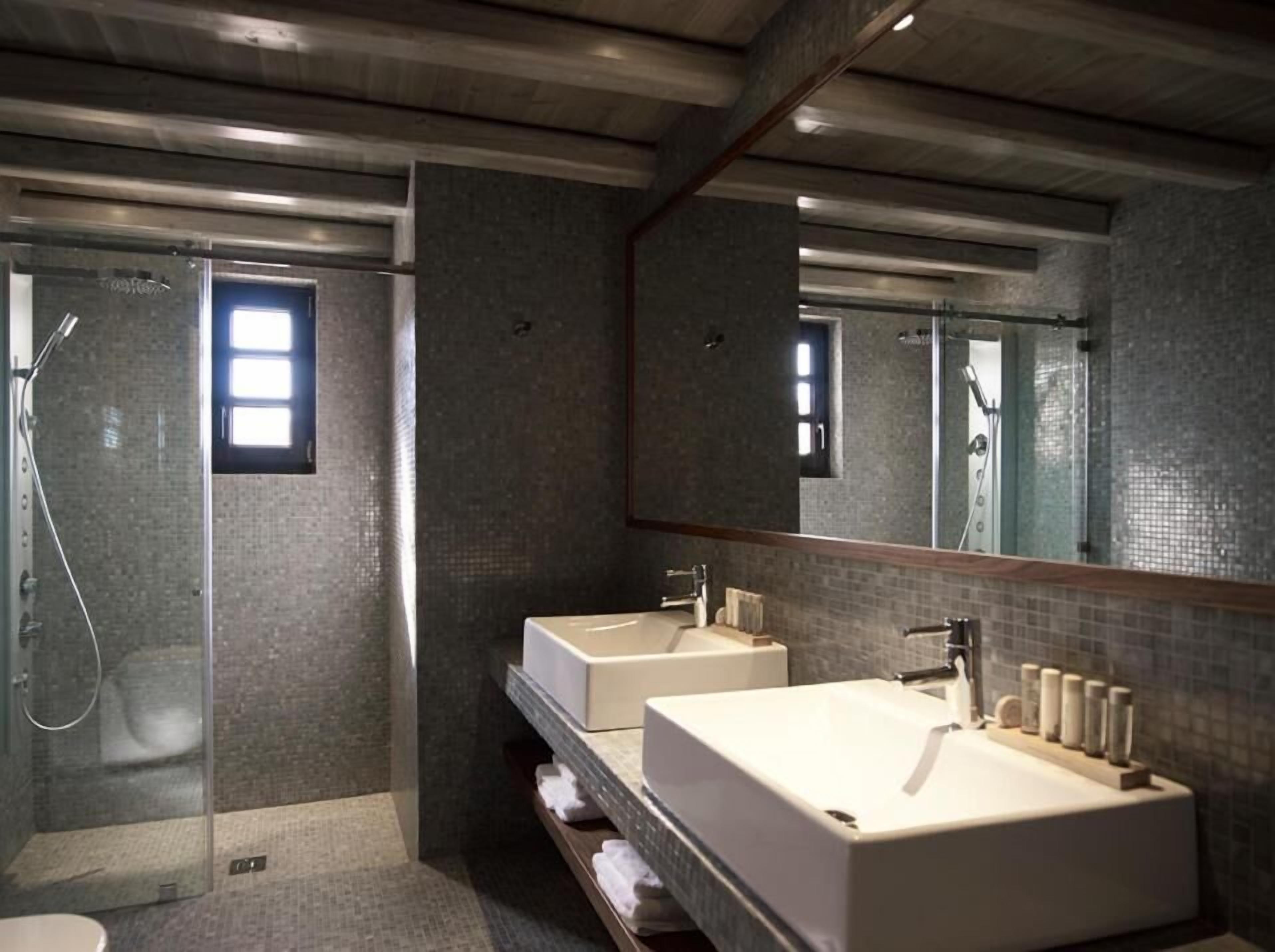 Un baño moderno con dos lavamanos, ducha y un espejo grande.