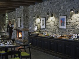 Una habitación con paredes de piedra, una chimenea, un bufé con diversas opciones de comida y obras de arte enmarcadas en las paredes.