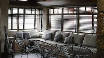 Ein modernes Interieur mit einem grauen Sofa, schwarzen Drahtgestellstühlen und einer Skulptur links.