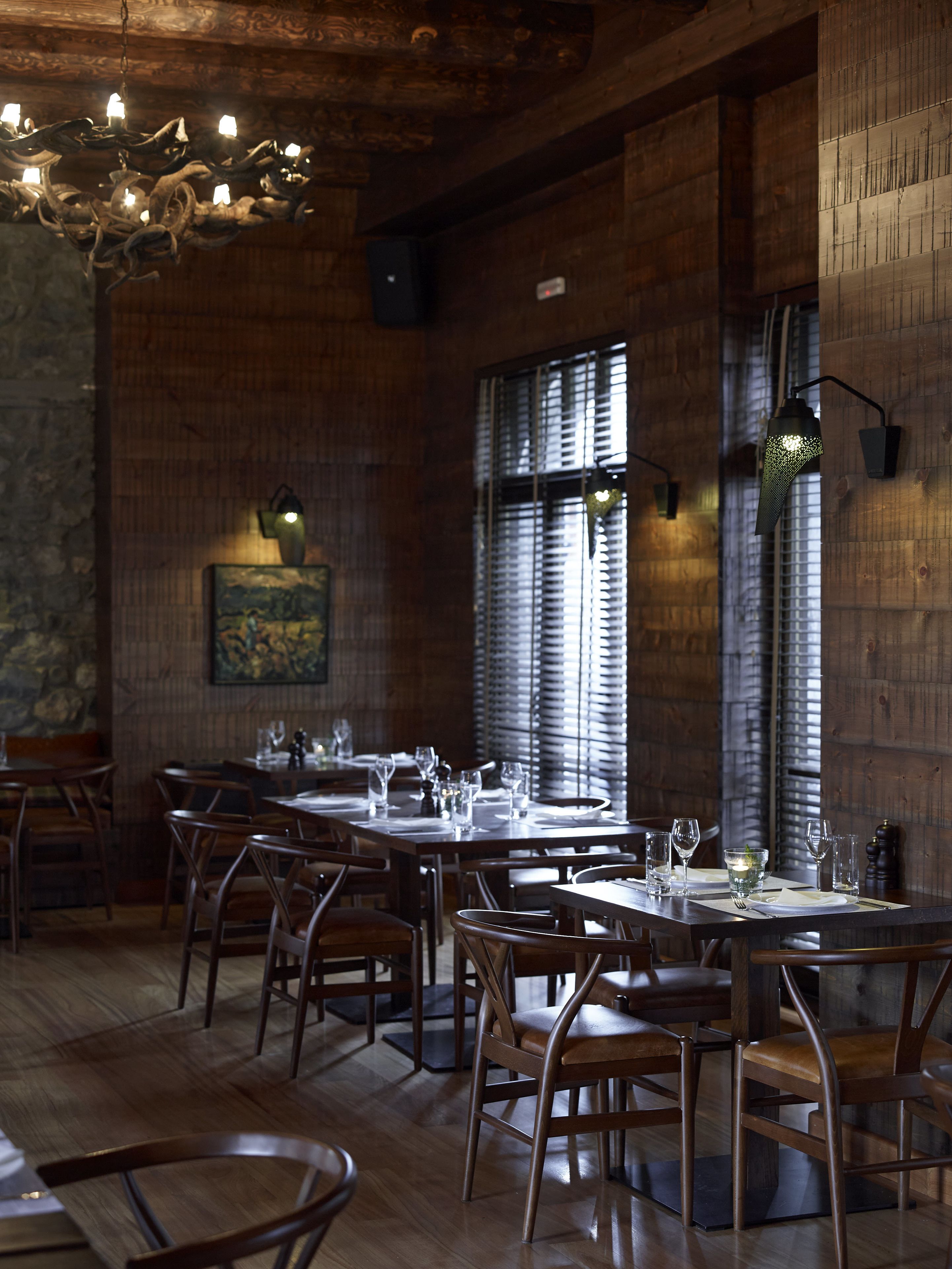 L’intérieur d’un restaurant, avec des murs en bois, un lustre et une salle à manger aménagée pour accueillir les clients.