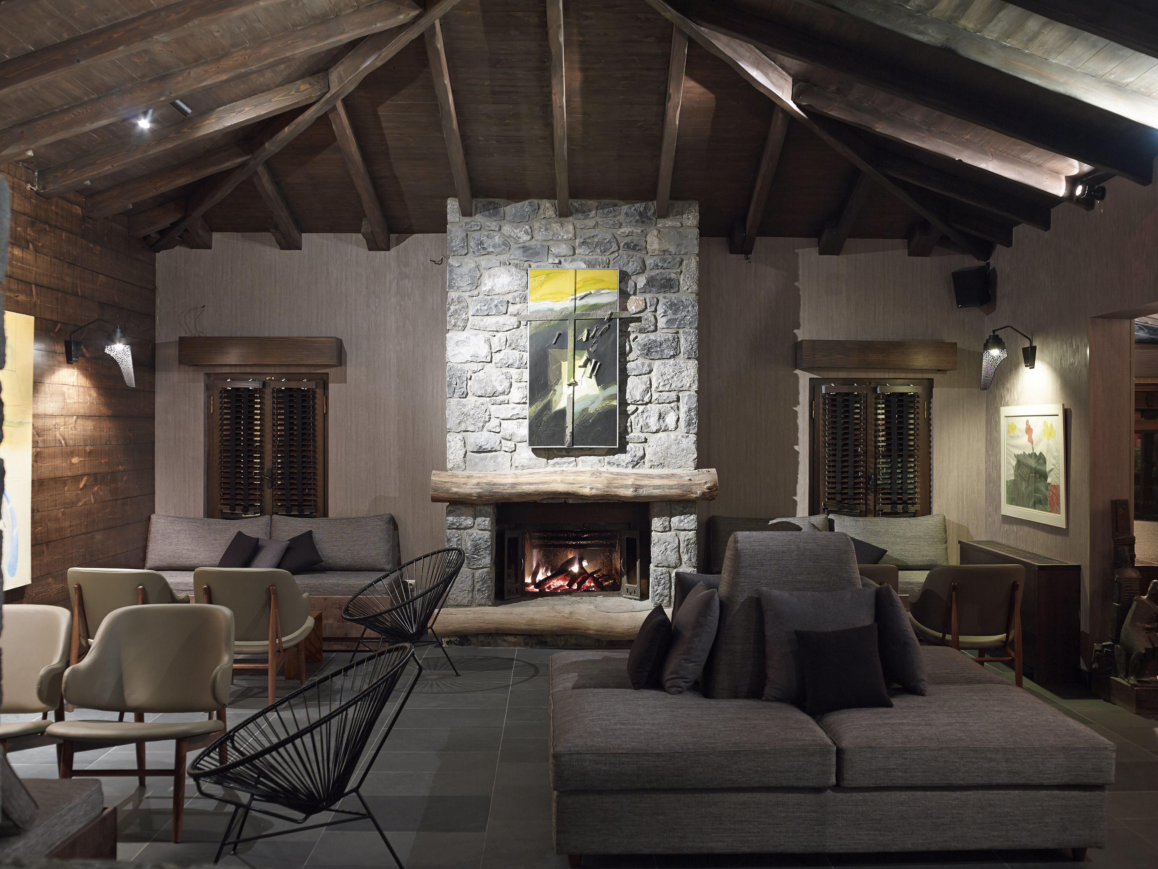 Una sala de estar acogedora con chimenea de piedra, vigas de madera y asientos cómodos.