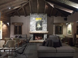 A cozy living room with a stone fireplace, wooden beams, and comfortable seating.