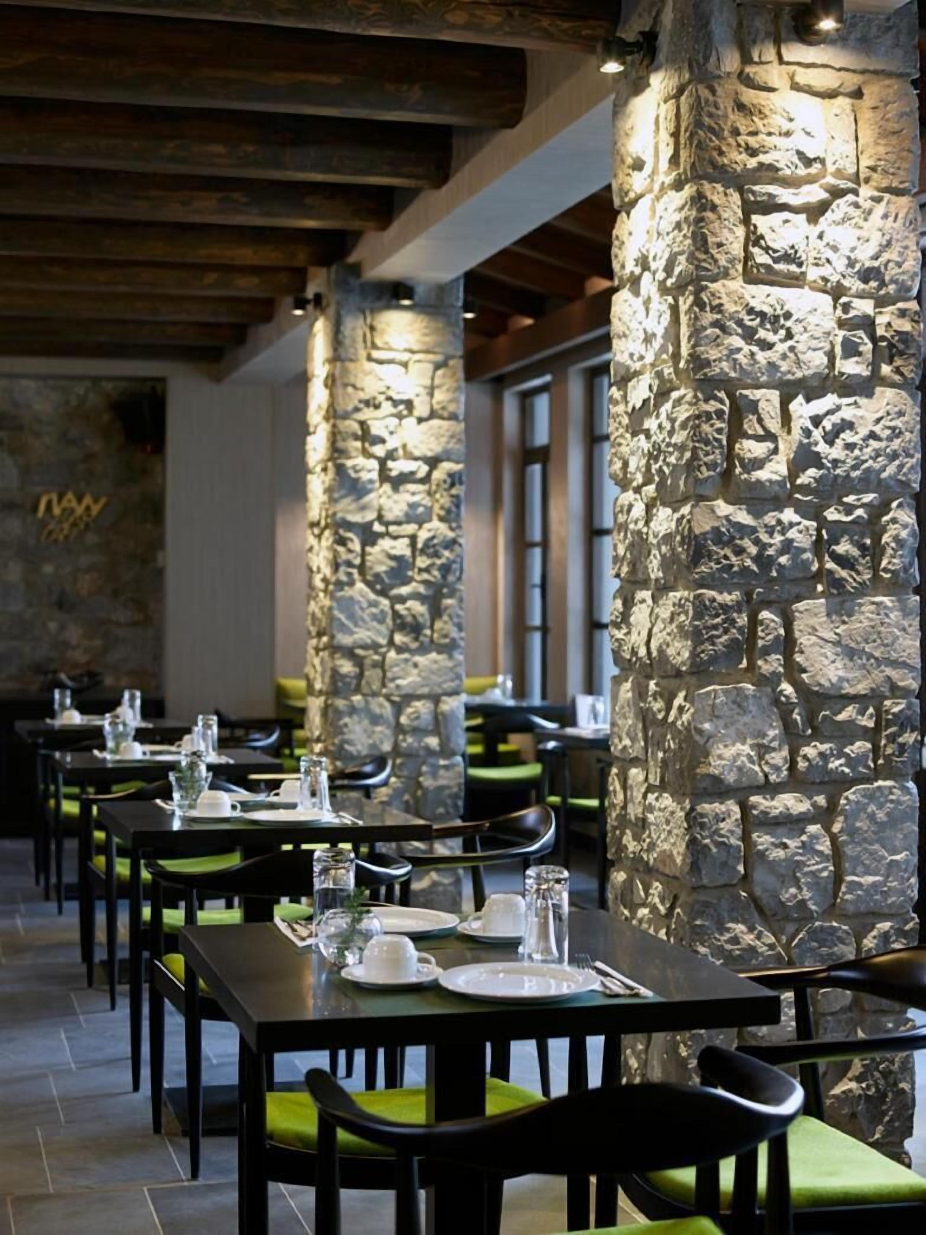 Un restaurante con pilares de piedra, vigas de madera y mesas dispuestas para comer.