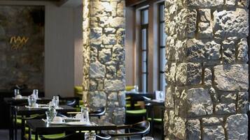 Un restaurante con pilares de piedra, vigas de madera y mesas dispuestas para comer.