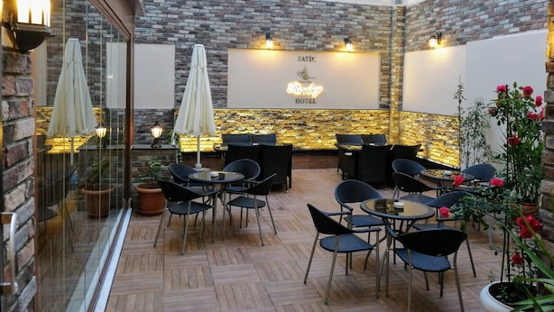 Un hall d’hôtel doté d’un mur en pierre, d’un comptoir d’accueil et de plusieurs espaces de détente avec des tables et des chaises.