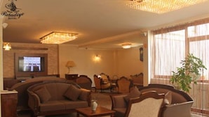 Un salon d’hôtel comprenant un ensemble de canapés, un téléviseur et un lustre.