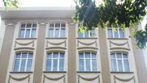Un immeuble à plusieurs étages de style architectural classique, doté de grandes fenêtres et de moulures décoratives. L’immeuble porte une enseigne indiquant « Faith Residences Hotel » et une autre précisant qu’il est en activité depuis 1924.