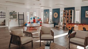 Amplia sala de estar con mesa de billar, asientos cómodos y una estantería.
