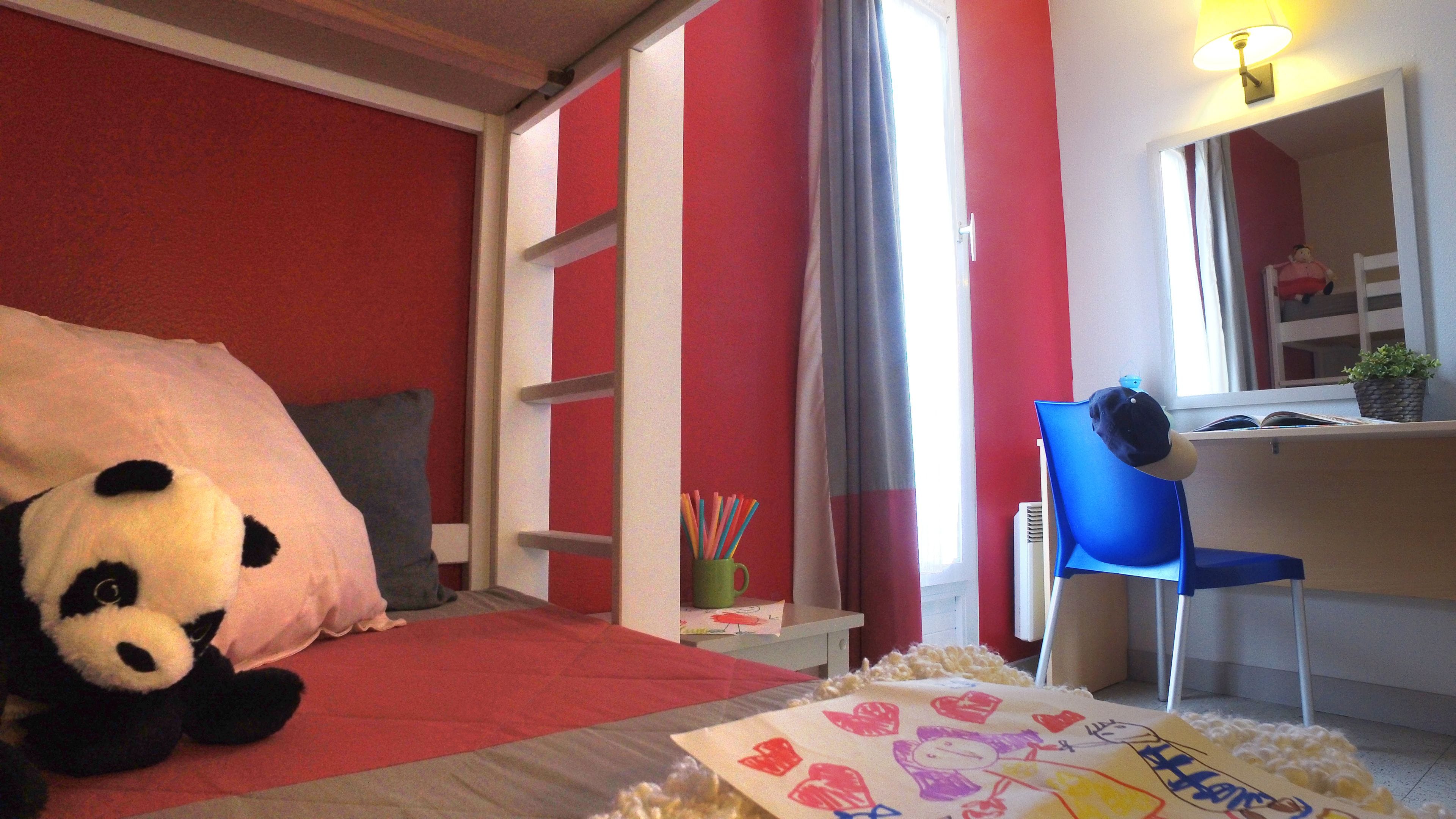 A bedroom with a bed, a desk, and a chair.